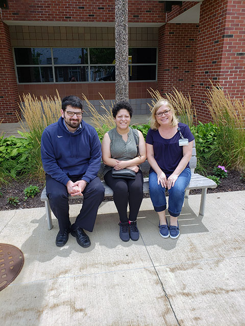 Three people on a bench smiling