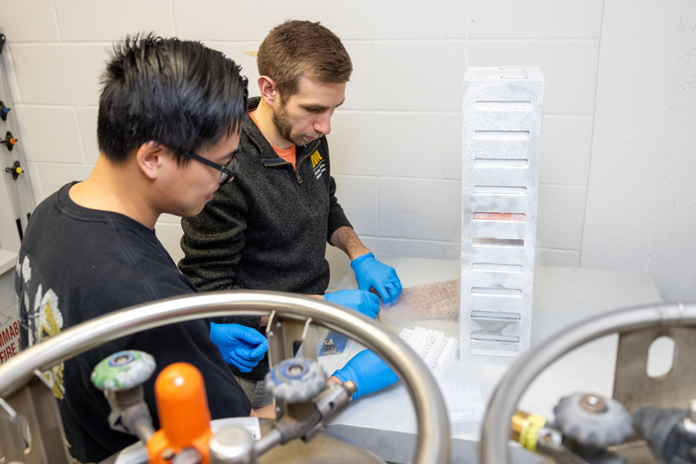 Two people operating lab equipment